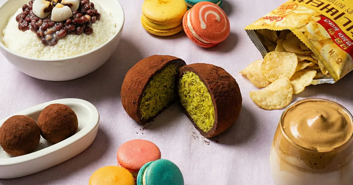 A variety of iconic Korean Desserts including Dubai Chewy Cookie, milk shaved ice, colorful fat macarons, and honey butter chips arranged on a table.