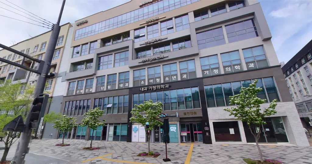 View of a modern multi-story building in a Korean city street with multiple clinic signs including pediatrics, internal medicine, and family medicine