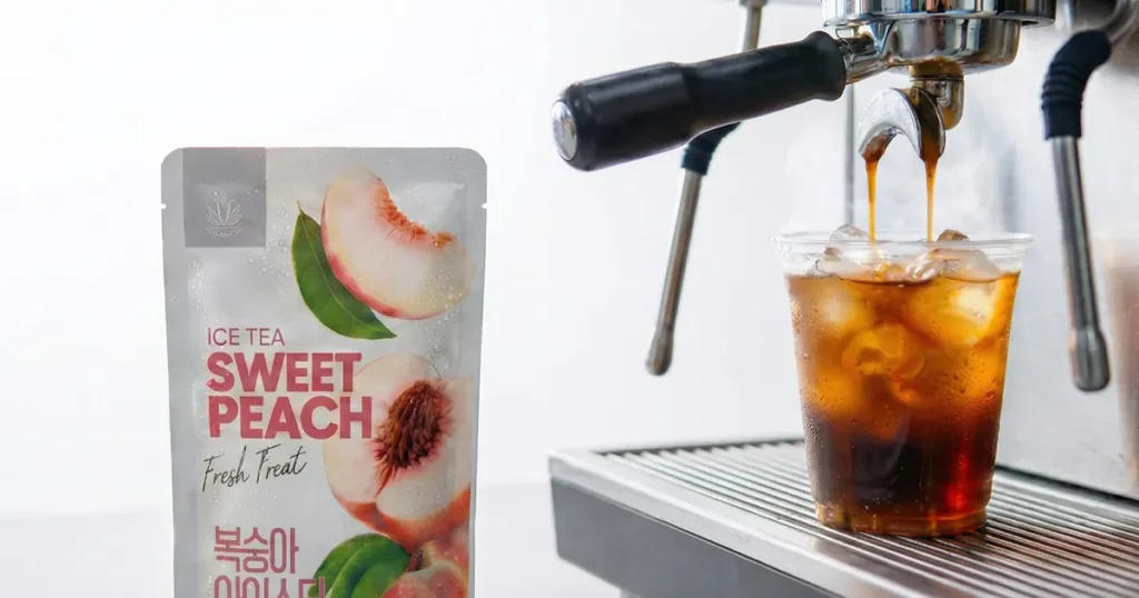 Peach iced tea and freshly poured espresso layered over ice in a clear plastic cup, illustrating a sweet-and-bitter Korean convenience store coffee mix.