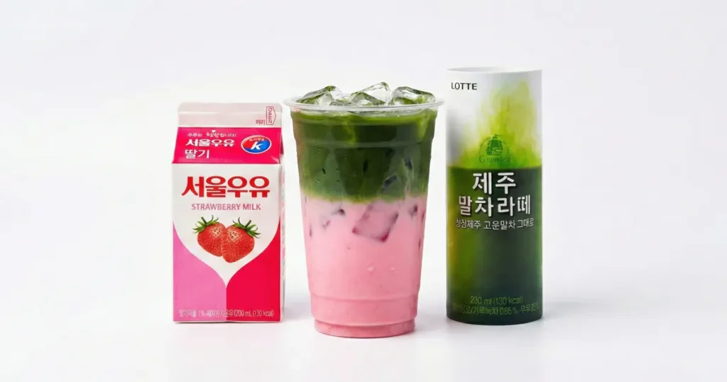 Strawberry milk and matcha latte placed beside a clear plastic cup showing pink strawberry milk layered with green matcha over ice, a colorful Korean convenience store DIY drink.